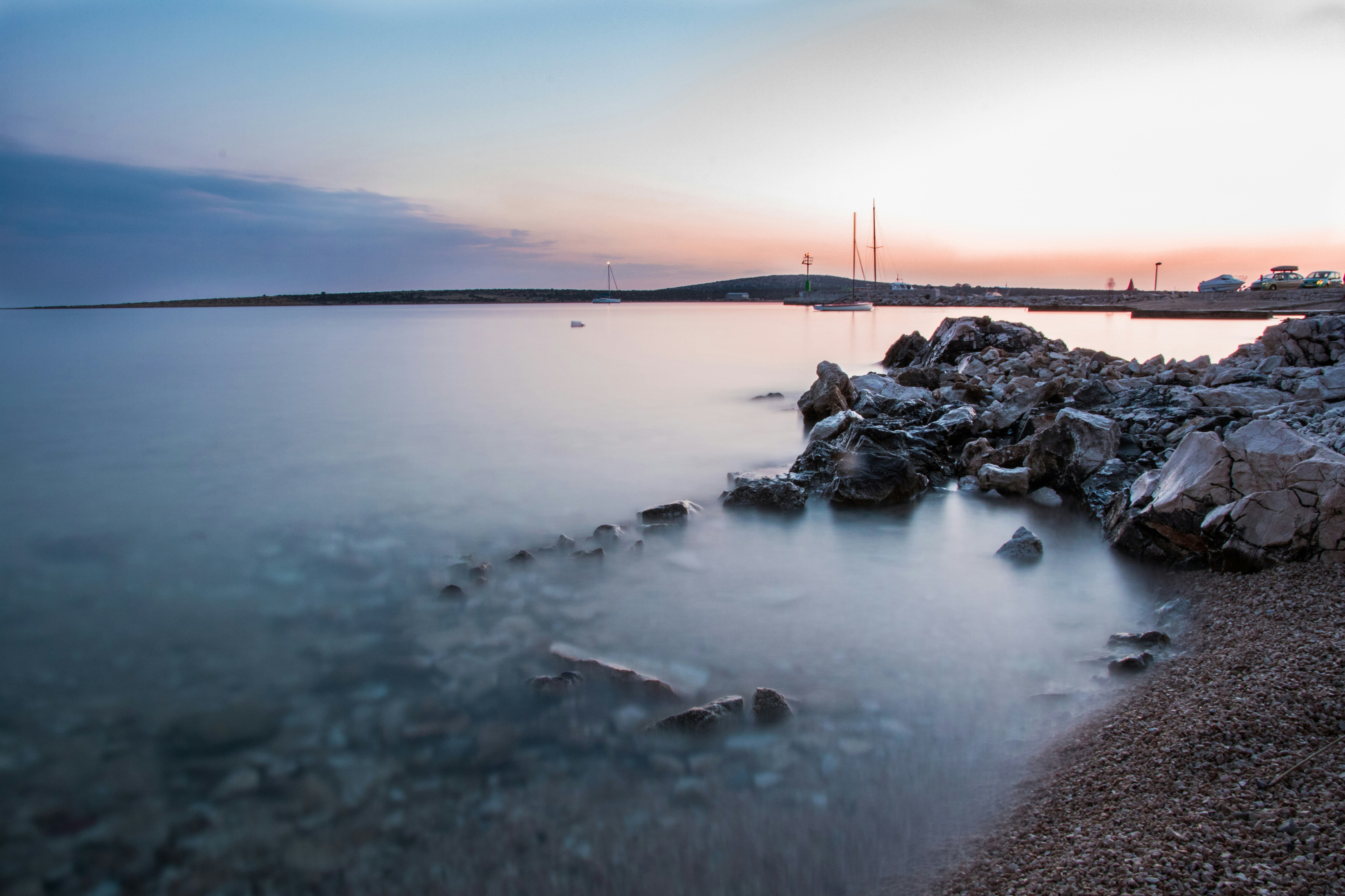 calm lake beside rock formation at daytime, This July I spent two and a half weeks in small place Košljun on the island of Pag. I just adore the peace and beauties of this place. And sunsets are always astonishing. You can find big spectre of colors everyday there. Purple, pink, blue, yellow and orange. This photo was taken in front of my apartment. Yes, beach is literally in front of it. I really enjoyed those two weeks with my family and boyfriend Petar. I am extremly greatful for living in Croatia.</p><p>I used my Canon 750D (would recommend it to everyone) and Sigma 17-50mm f/2.8 (dude, those lens are love of my life).
