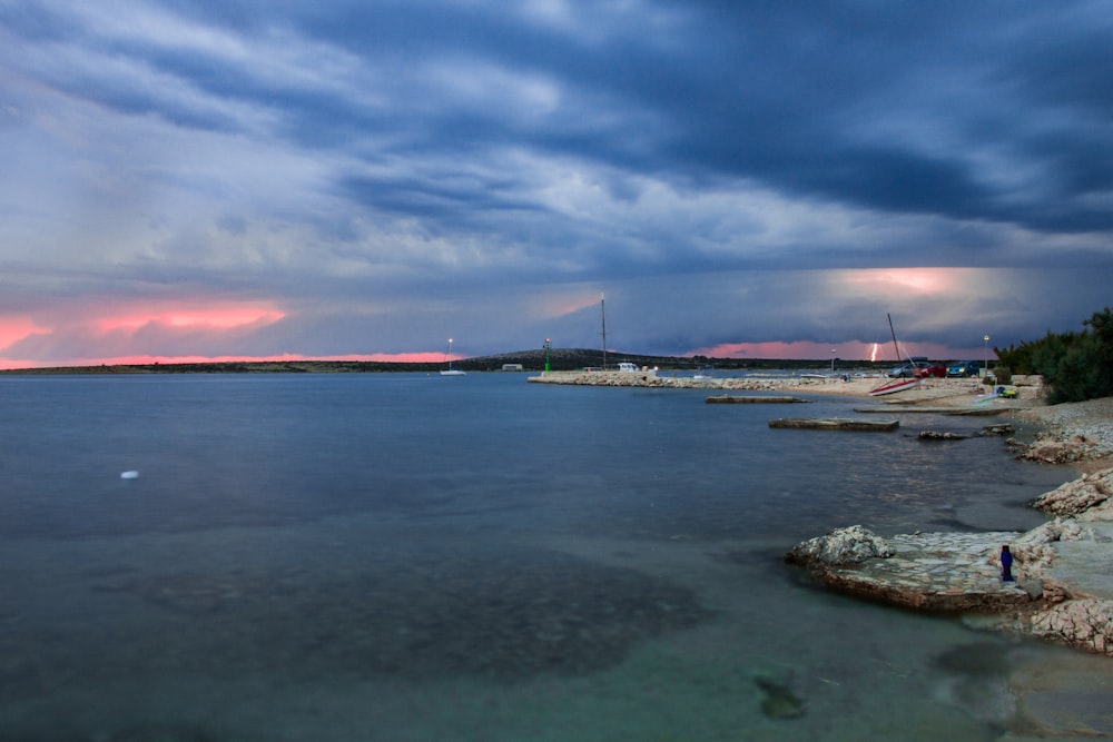 white boat on sea under cloudy sky during daytime