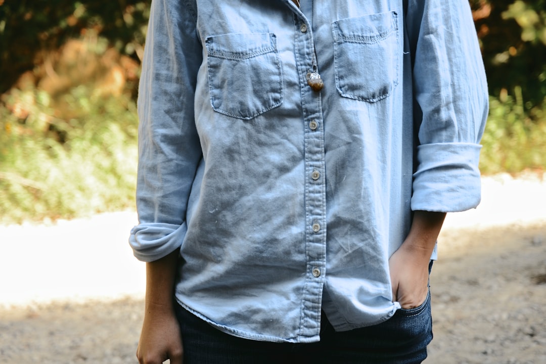 Person's torso wearing a denim chambray shirt with cuffed sleeves
