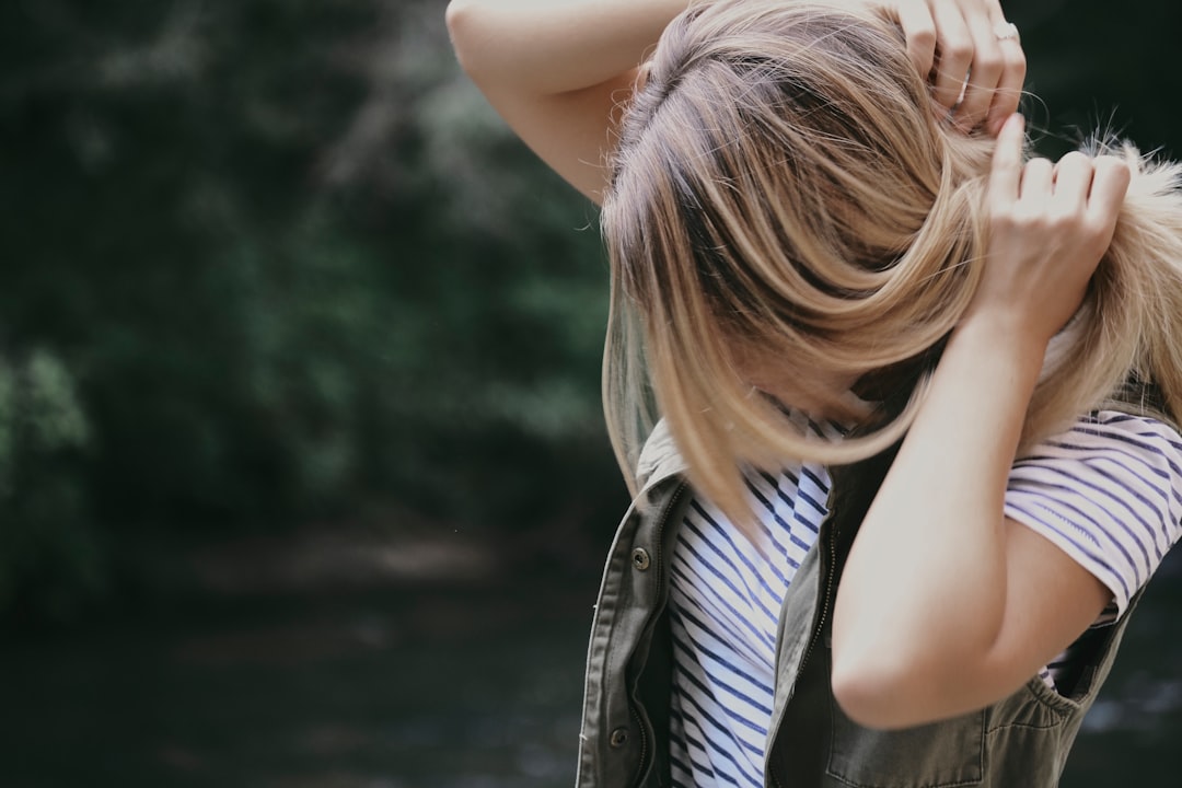 photography of a woman in striped shirt fixing her hair