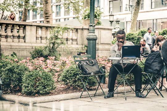 A friendly community member using a laptop outdoors in a Bogotá neighborhood.