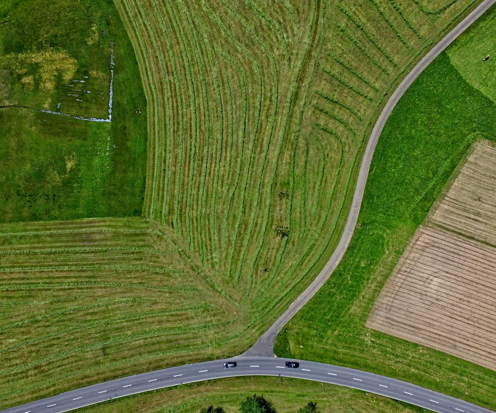 Luftaufnahme der grauen Asphaltstraße in der Nähe der grünen Wiese während des Tages