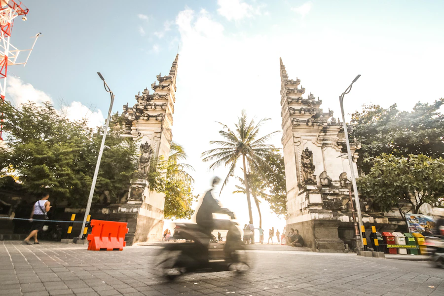 Rider on a Balinese street with a traditional gate near Uluwatu