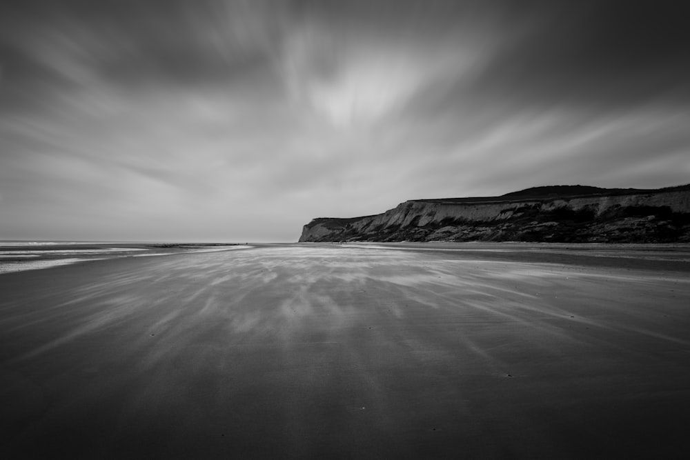 grayscale photo of seashore and mountain