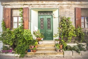 A welcoming entrance of a Lucknow BnB with vibrant plants and a rustic wooden door.