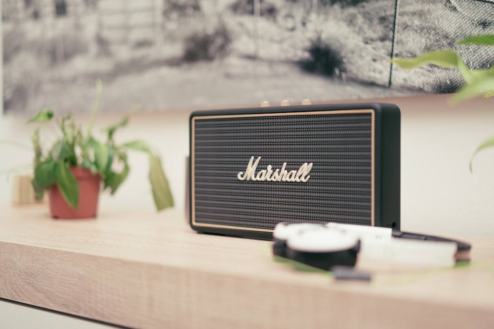 black Marshall Bluetooth speaker on top of brown table