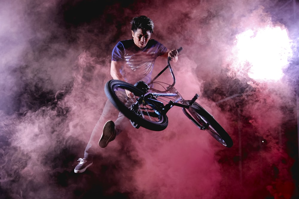 Hombre haciendo truco de bicicleta rodeado de niebla roja