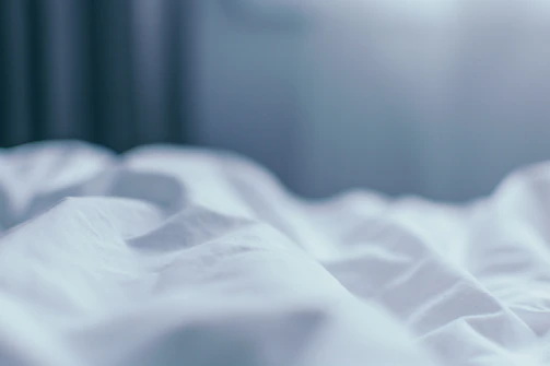 Close-up of a sleek white noise machine emitting gentle waves of sound in a dimly lit room.