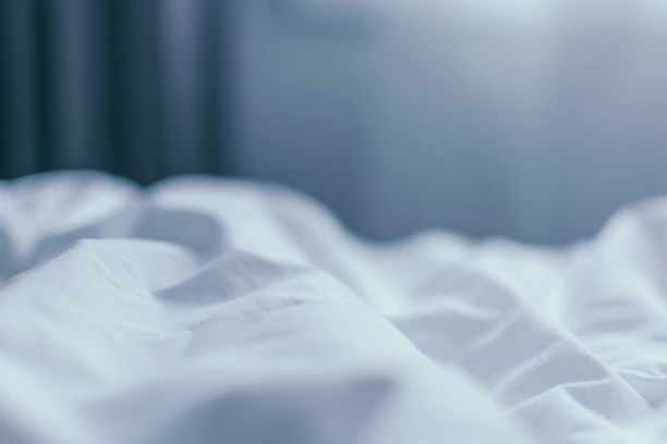 A delicate silk sheet draped over a plush bed, bathed in warm, golden light.