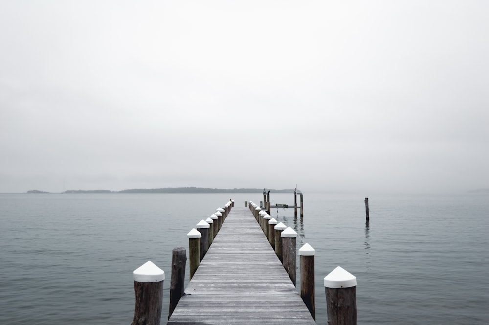 gray wooden dock far from mountain at daytime