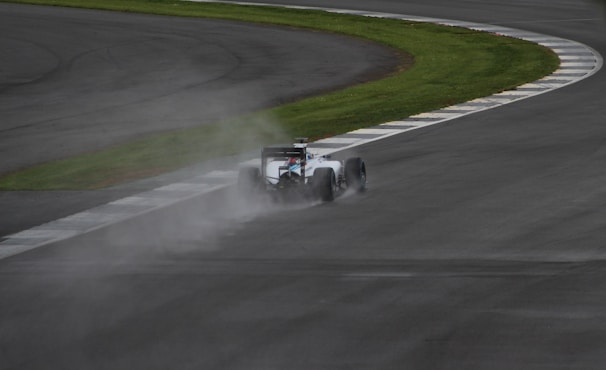 A dramatic shot of a Formula 1 car speeding on a wet racetrack.