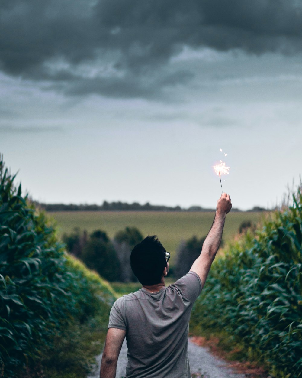 man standing on pathway holding sparkler