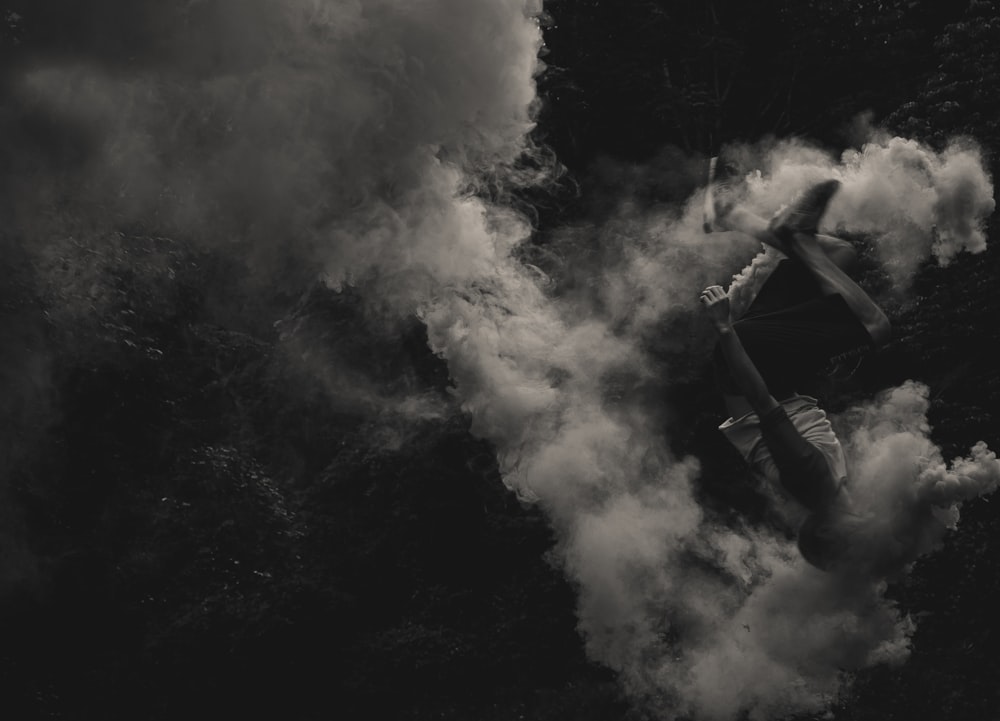 Una persona haciendo una voltereta hacia atrás a través de una nube de humo.