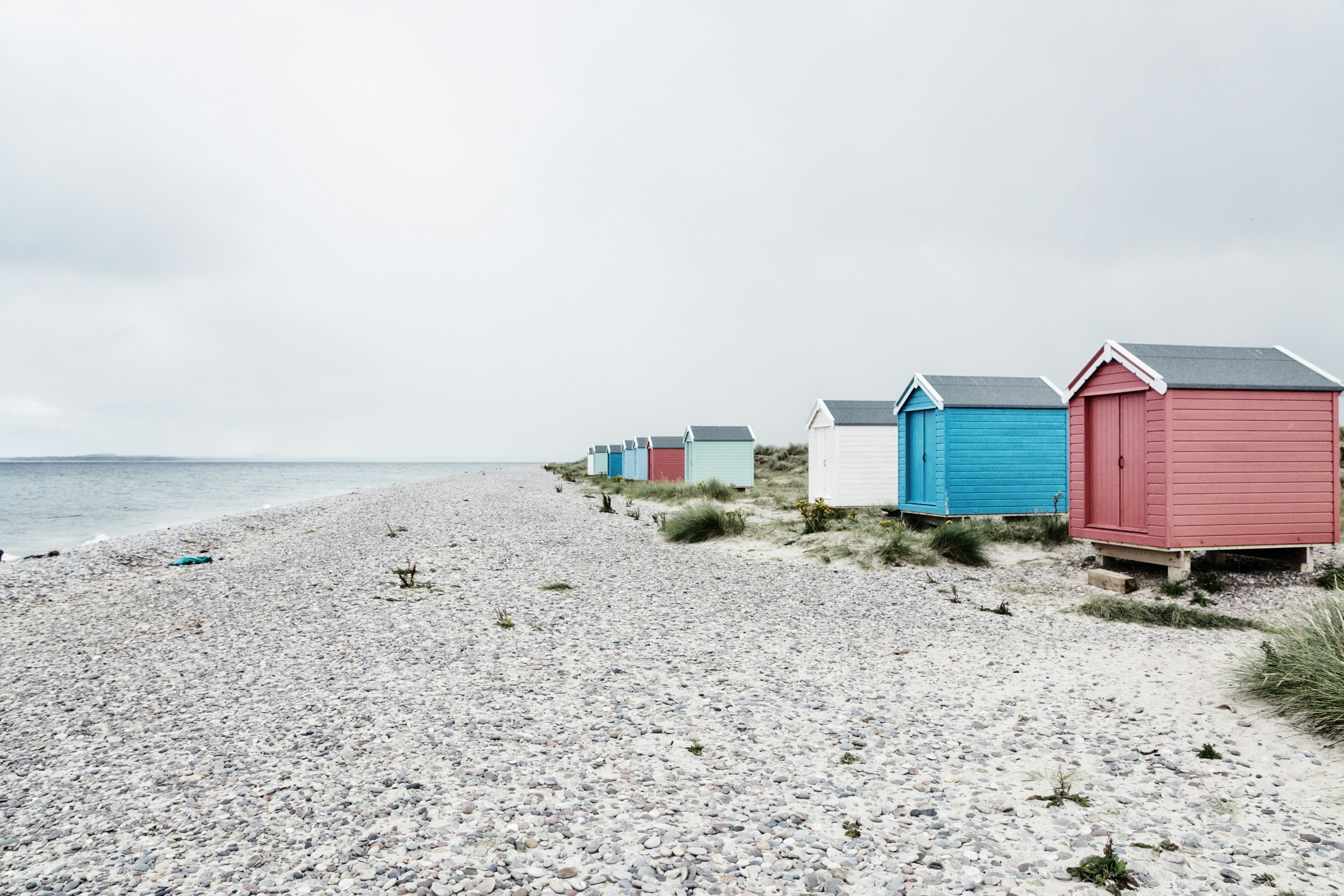 assorted-color sheds near seashore at daytime