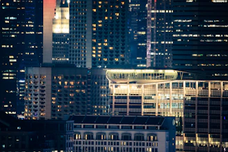 A sleek nighttime cityscape highlighting illuminated building infrastructure with visible HVAC and electrical systems.