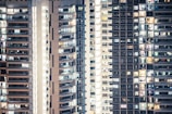 High-rise apartment buildings with numerous windows, some illuminated and others dark, creating a pattern of light and shadow. The structures appear to be densely packed, showcasing urban residential living.