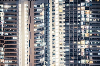 High-rise apartment building with floor-to-ceiling windows reflecting city lights.