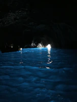 A tight cavern opening with softly glowing blue waters inside.
