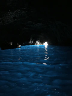 A tight cavern opening with softly glowing blue waters inside.