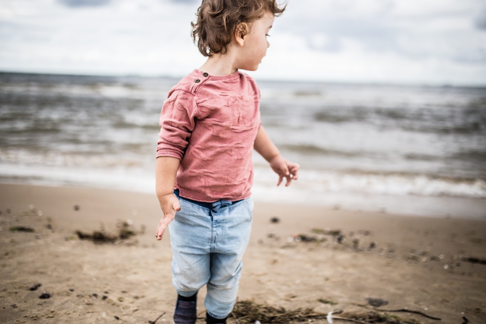 toddler boy standing on seashore