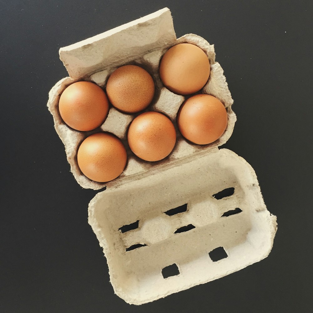 Seis huevos de ave marrón en bandeja