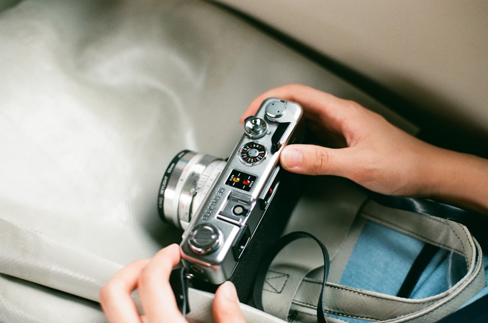 person holding gray and black DSLR camera