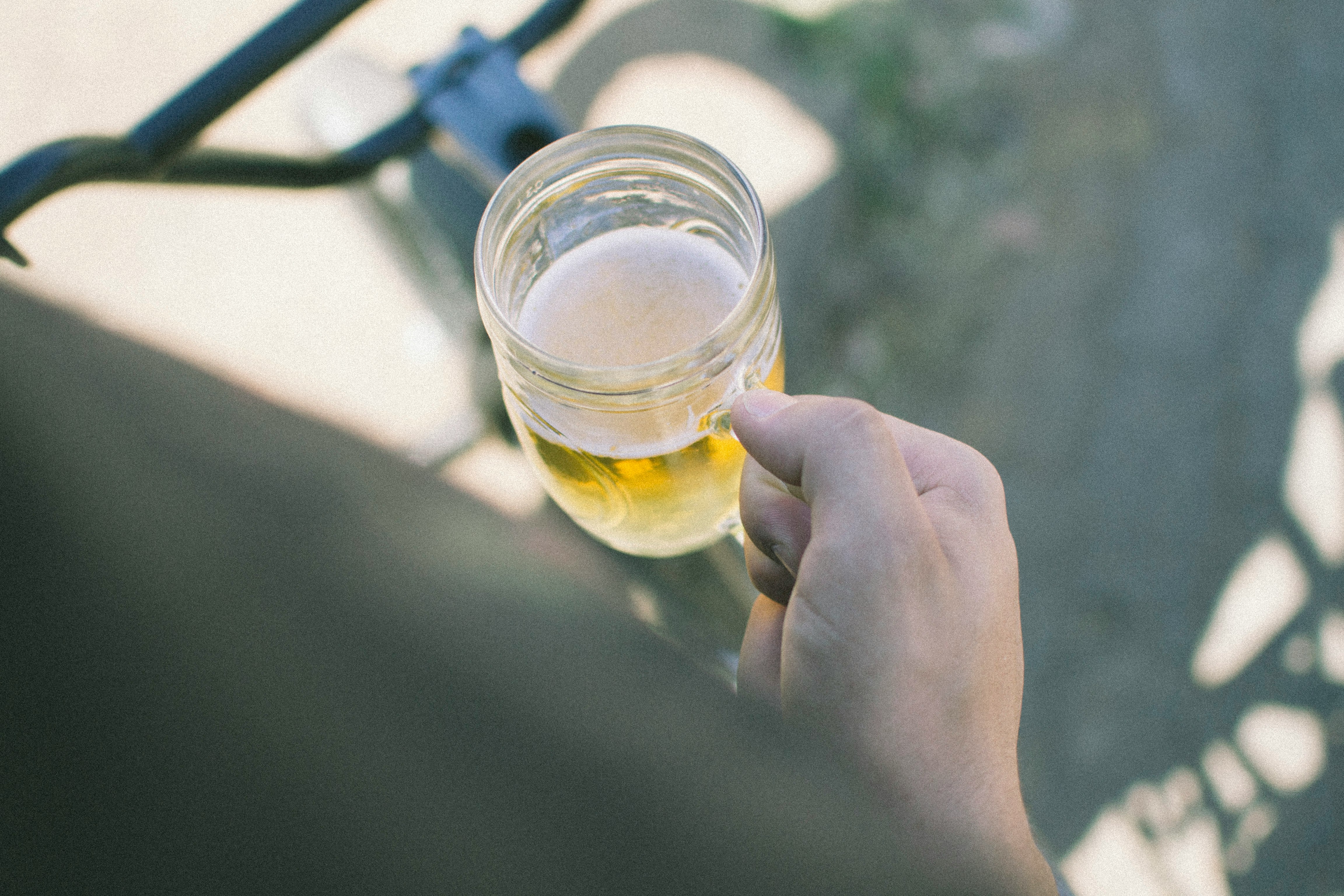 person holding clear glass mason mug