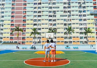 minimalist photography of two men standing on basketball court looking upwards