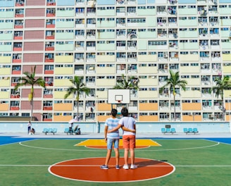 minimalist photography of two men standing on basketball court looking upwards