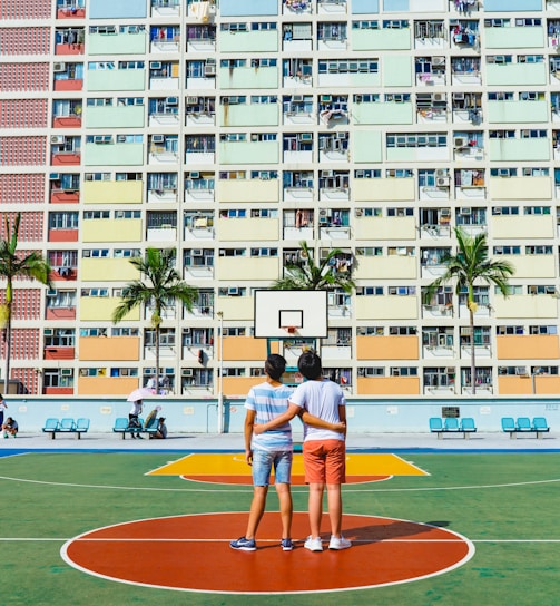 minimalist photography of two men standing on basketball court looking upwards