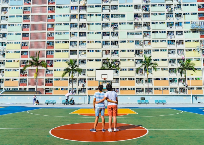 minimalist photography of two men standing on basketball court looking upwards