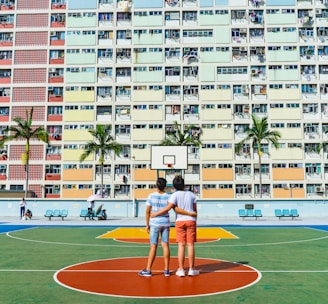 minimalist photography of two men standing on basketball court looking upwards