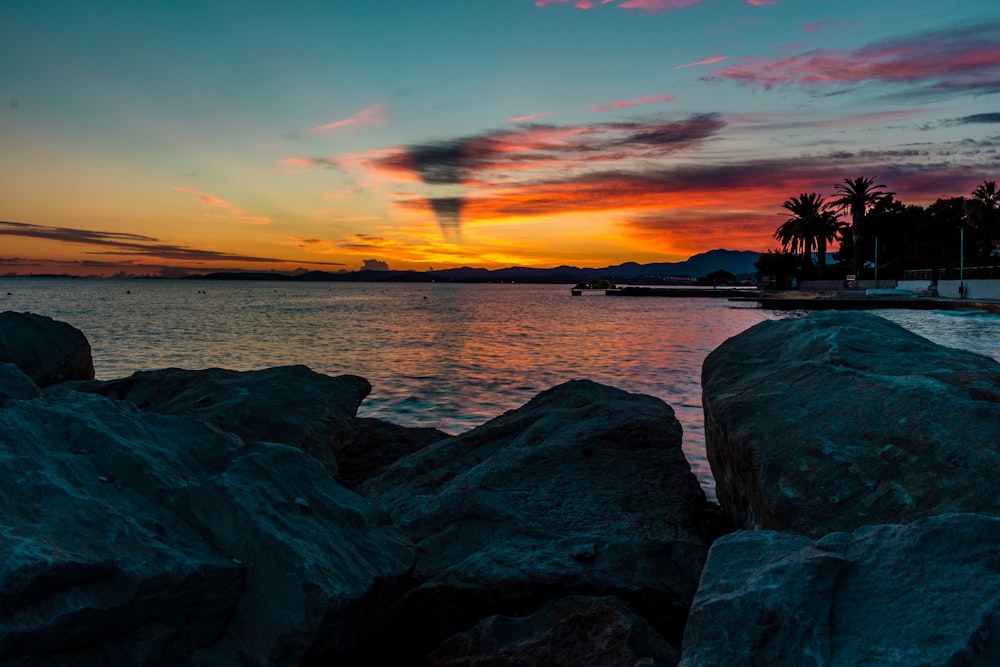 a sunset over a body of water with rocks