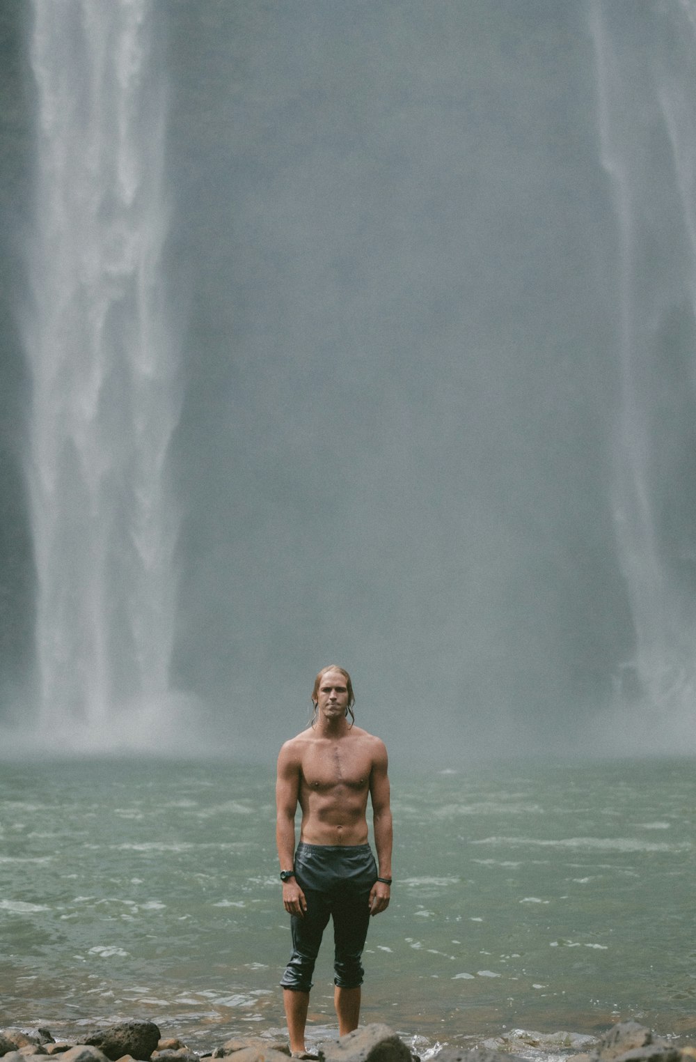 目の前の滝に立つトップレスの男