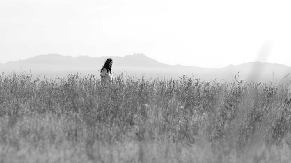 Photographie en niveaux de gris d’une femme sur des champs