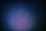 A vast expanse of outer space filled with countless small stars scattered across a dark backdrop. A subtle gradient of colors ranging from deep blue to purple envelops the scene, giving it a mystical appearance.