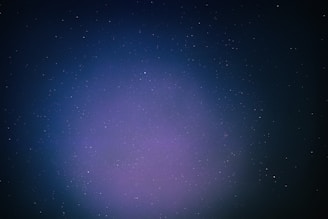 A vast expanse of outer space filled with countless small stars scattered across a dark backdrop. A subtle gradient of colors ranging from deep blue to purple envelops the scene, giving it a mystical appearance.