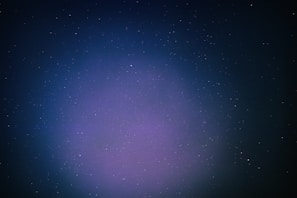 A vast expanse of outer space filled with countless small stars scattered across a dark backdrop. A subtle gradient of colors ranging from deep blue to purple envelops the scene, giving it a mystical appearance.
