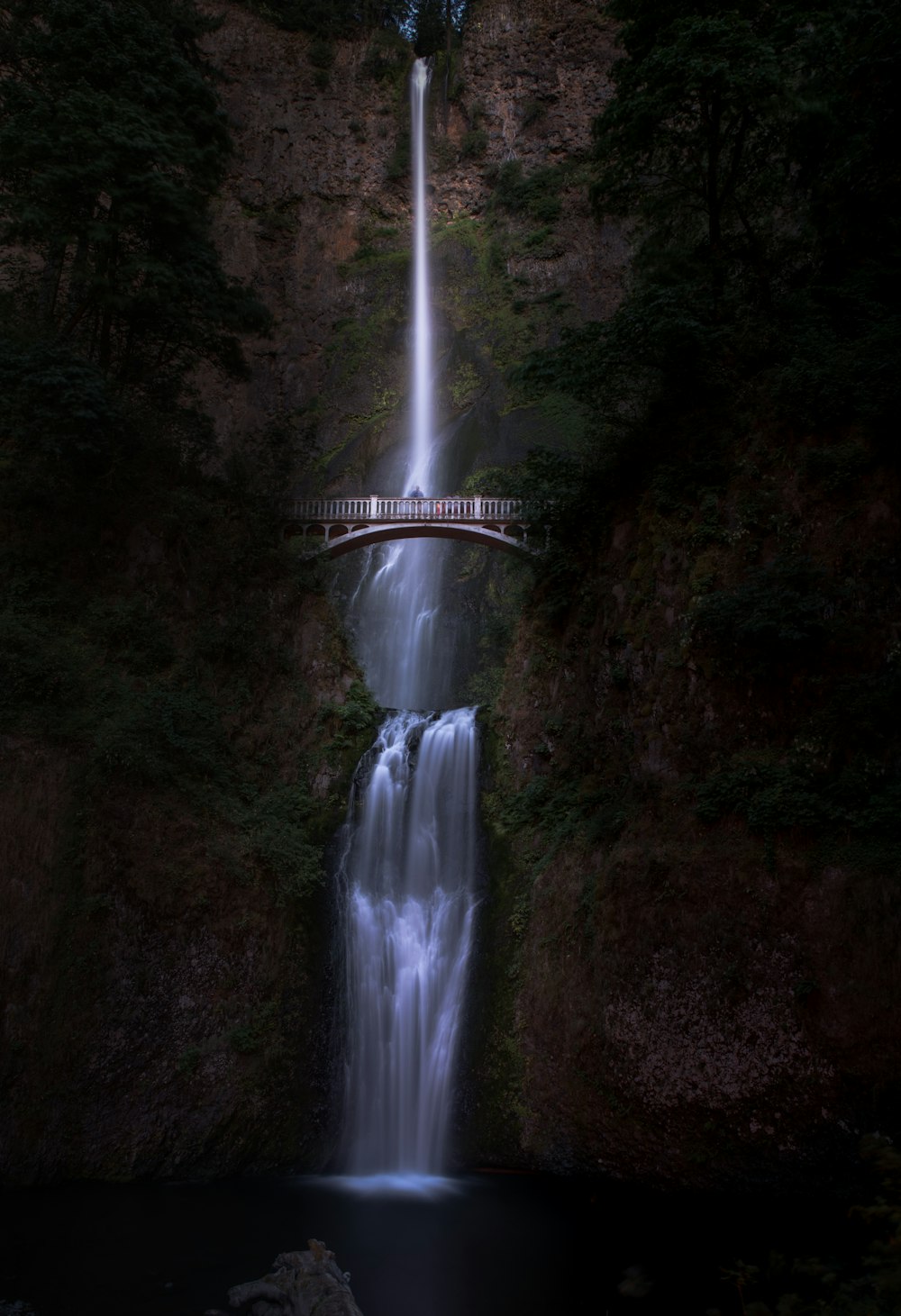 bridge near waterfalls at daytime