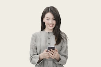 Woman with long, healthy hair smiling while using a smartphone in a bright room