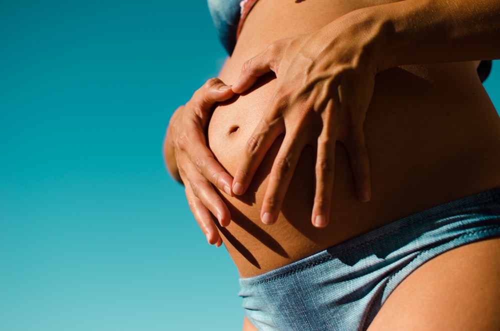 Fotografía de primer plano de mujer embarazada con braga azul