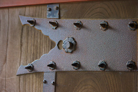 Close-up of metallic door hinges and clamps arranged on a sleek industrial surface.
