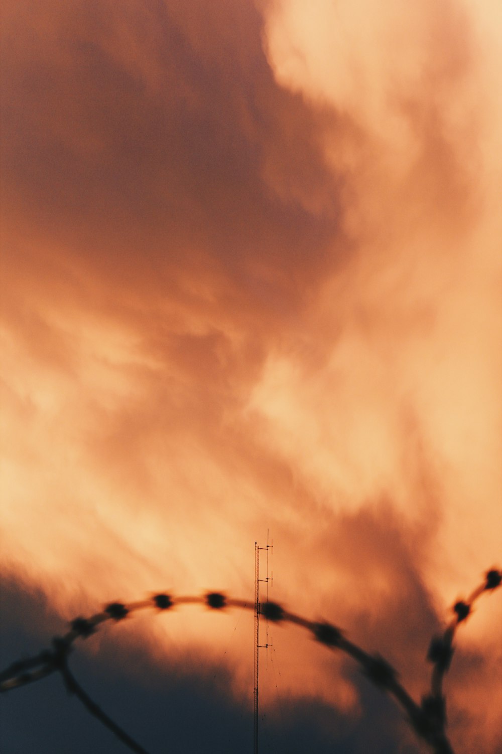 a barbed wire fence with a sky in the background