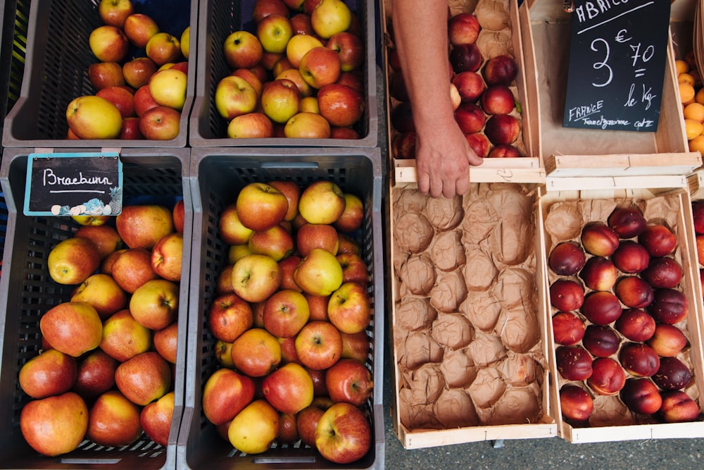 rote Apfelfrüchte auf schwarzen Plastikkisten