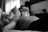 grayscale photo of man laying on bed
