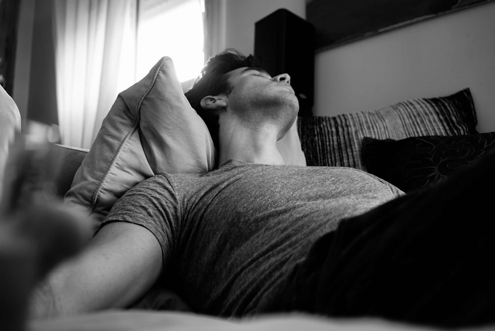 grayscale photo of man laying on bed