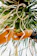 A close-up of hands weaving natural fibers against a backdrop of coastal greenery.