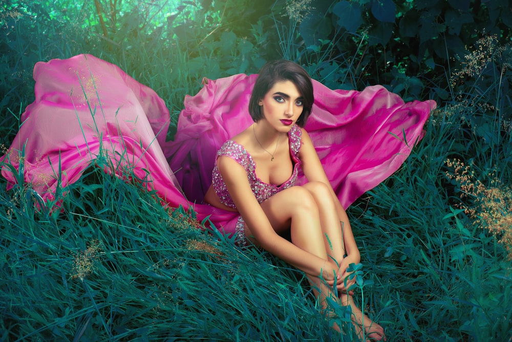 woman in pink dress lying on green grass