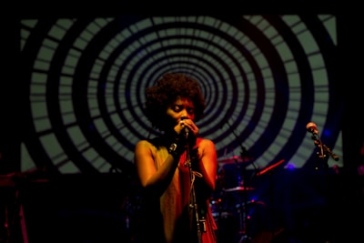 A close-up shot of Stephanie Sanders Heir performing on stage, bathed in warm amber light that highlights her soulful expression.