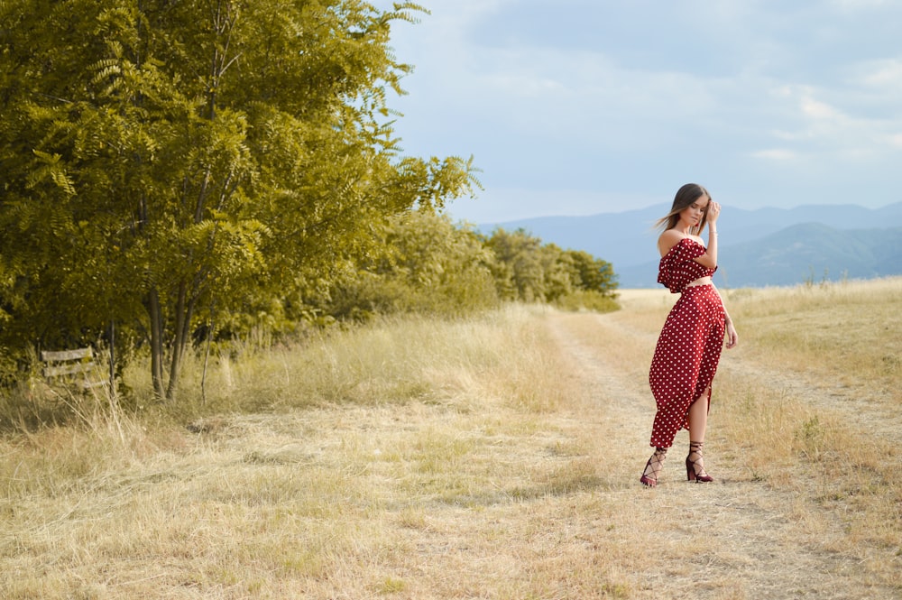 woman standing beside green trees touching her hair